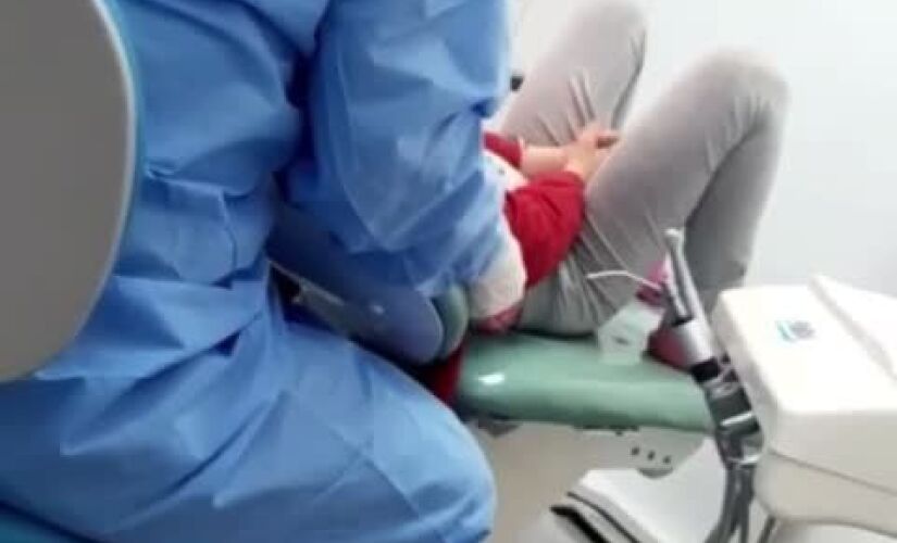 A mãe conta que entrou na sala de atendimento com a filha e ficou sentada em uma cadeira atrás da dentista