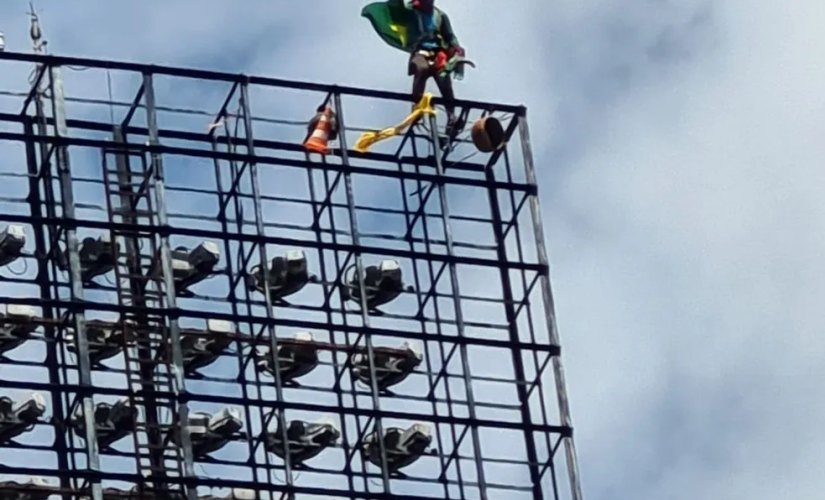 Homem protestou envolto a uma bandeira do Brasil em cima de refletor de estádio