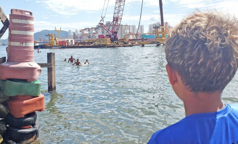 Crianças insistem em brincar na porta para o mar que ainda resta no Sítio Conceiçãozinha, em Guarujá, que vem perdendo espaço