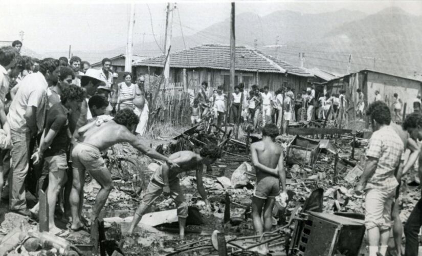 Homens retiram objetos pessoais em meio aos destroços após incêndio na Vila Soco, em Cubatão