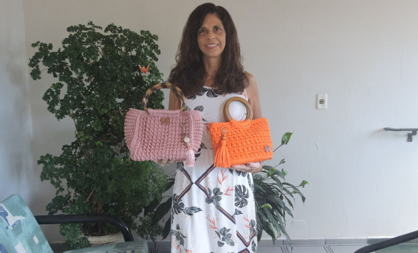 A artesã Célia Regina mostra as bolsas feitas em crochê de vários modelos e cores, em Itanhaém