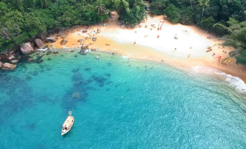 A pequena faixa de areia é cercada por intenso verde e mata fechada 