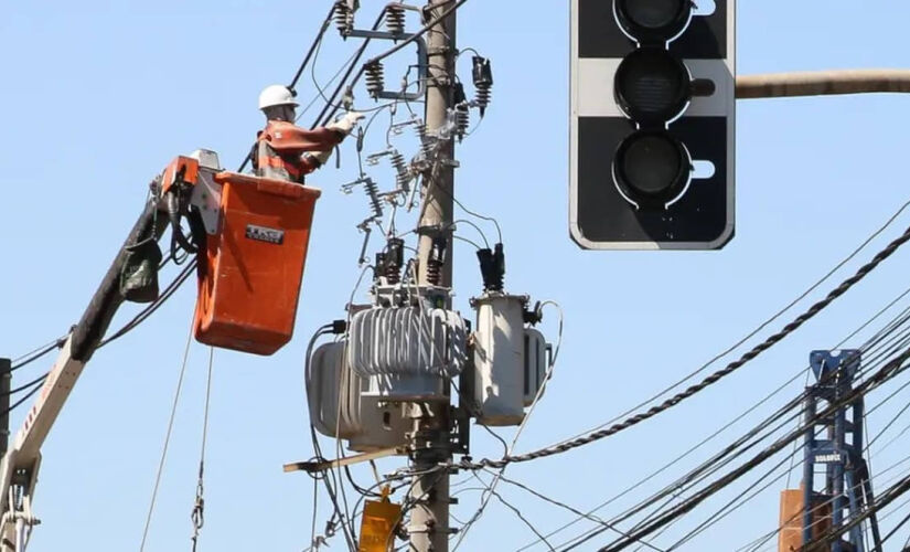 Funcionário da Enel trabalhando em um poste na capital de SP