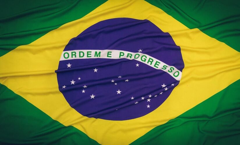 Com o retângulo verde, o losango amarelo e o círculo azul em destaque, a bandeira possui 27 estrelas dentro da parte azulada