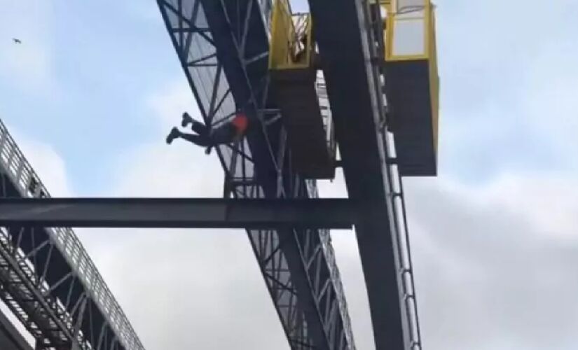 Imagens publicadas nas redes sociais mostram o trabalhador balançando, preso pelo cinto de segurança