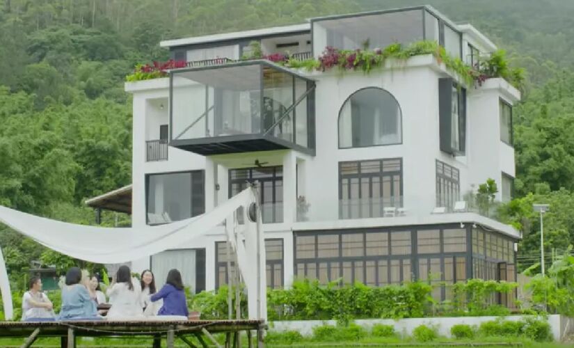 Casa, que ocupa três andares e meio, está situada em uma área cercada por colinas e arrozais