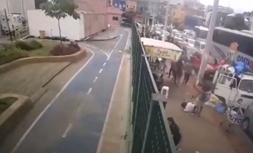 Vídeo de câmera de segurança mostra o momento em que um homem de camiseta branca cai no chão e é alvejado por outro