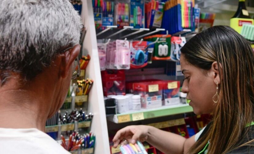 Vendedora da papelaria Femapel ajudando um cliente a comprar o material escolar, na capital paulista 