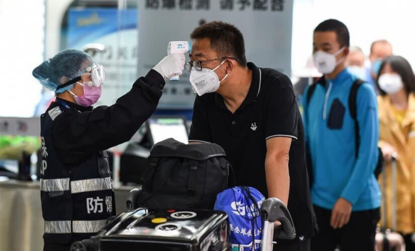 Pessoas usam máscaras e passam por verificação de temperatura em aeroporto na China