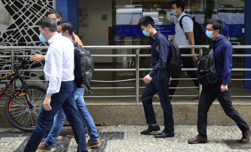 Pedestres utilizam m&aacute;scaras de prote&ccedil;&atilde;o contra o novo coronav&iacute;rus