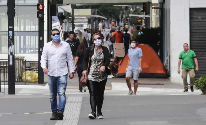 Pessoas caminham com m&aacute;scara de prote&ccedil;&atilde;o na avenida Paulista; Capital e Grande S&atilde;o Paulo seguem na fase amarela