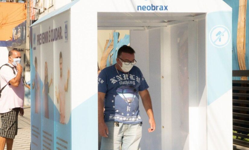 Usuário passa por dentro da cabine para se desinfectar
