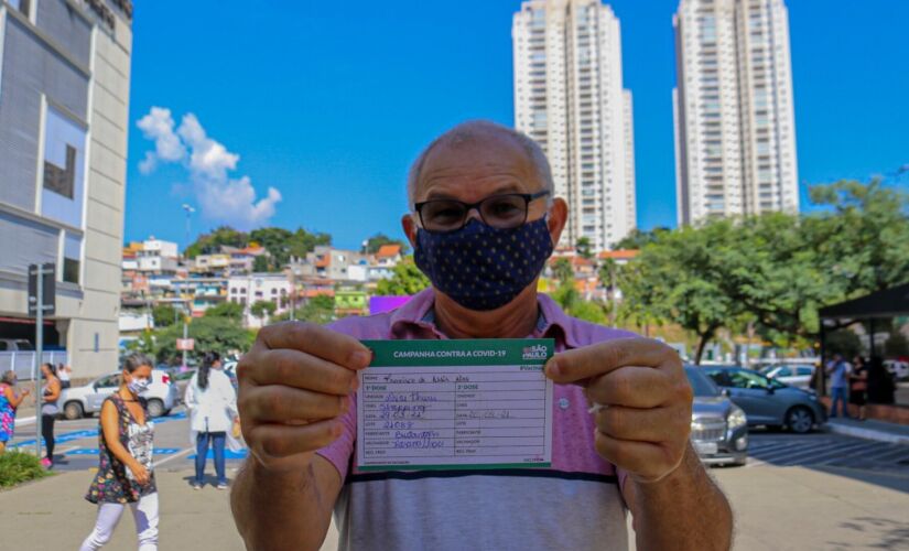 Homem exibe cart&atilde;o ap&oacute;s ser vacinado no Shopping Tabo&atilde;o