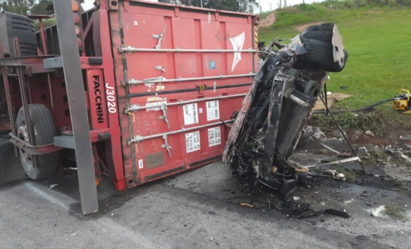 O motorista bateu na carreta que, com o impacto da batida, acabou tombando e derrubando o contêiner em cima do veículo