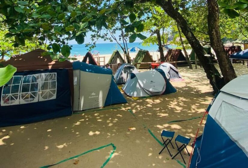 Fundado pela tradicional família caiçara de Seu Cacau e Dona Verônica, o camping oferece uma estrutura básica, mas acolhedora, com restaurante, bar, banheiros com chuveiros e muita sombra das árvore. Foto: Divulgação