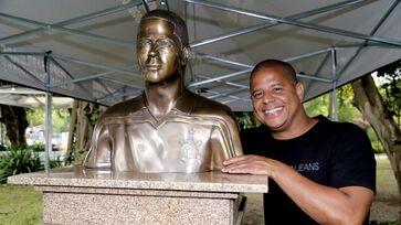 Marcelinho Carioca posa ao lado de busto em sua homenagem