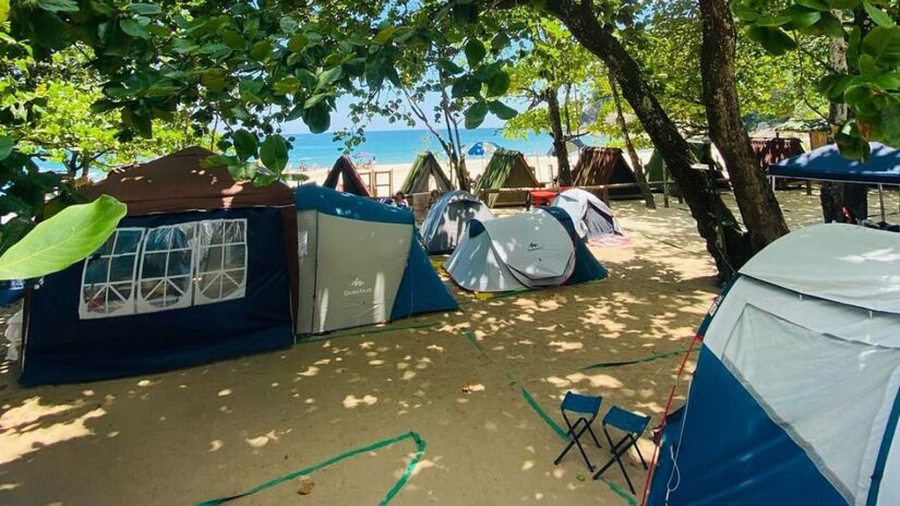 Fundado pela tradicional família caiçara de Seu Cacau e Dona Verônica, o camping oferece uma estrutura básica, mas acolhedora, com restaurante, bar, banheiros com chuveiros e muita sombra das árvore. Foto: Divulgação