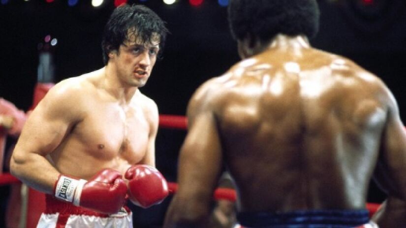 6. Rocky, um lutador - Fechando a lista com o filme mais famoso, que lançou Sylvester Stallone ao estrelato, em 1976. O longa, que tem o roteiro feito pelo próprio Stallone, ajudou a popularizar os filmes com temática esportiva e se tornou a franquia de luta mais famosa de todos os tempos. Rocky Balboa, um pequeno e pobre jovem encontra no boxe sua chance de mudar de vida. Ele é escolhido para enfrentar o atual campeão, Apollo Creed, em uma luta histórica - (Reprodução)