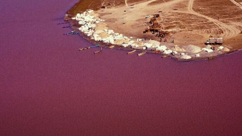 Lago Retba - Senegal: Semelhante ao lago anterior, o Retba, em Senegal, também é excessivamente salgado. Porém, neste local, o índice é muito mais alto. A salinidade é tão alta, que para coletar o sal, é necessário utilizar manteiga de karité para evitar irritações na pele devido à exposição prolongada - (Reprodução/YouTube)