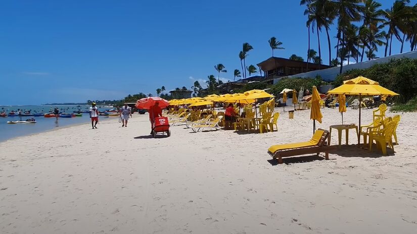 Com extensas faixas de areia macias e águas mornas e rasas, a praia oferece a oportunidade perfeita para nadar, tomar sol e relaxar - (Reprodução/Youtube)