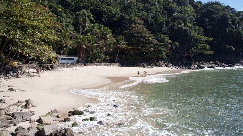 Uma das boas opções é a Praia do Éden, que possui acesso restrito, feito por trilha e escadaria, o que contribui para um clima de exclusividade. O destino possui um mar calmo e de águas cristalinas, ideal para quem deseja fugir do movimento intenso das praias centrais - (Divulgação/Secretaria de Turismo do Guarujá)