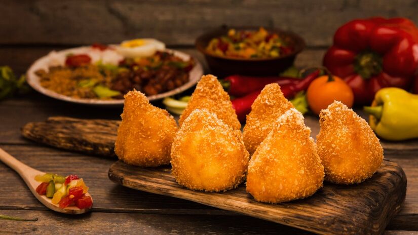 Você prefere começar pela ponta ou pela base? Bom, não importa como você come, muito menos qual tamanho, formato ou recheio prefere, a verdade é que a coxinha é o quitute mais popular e mais amado pelos brasileiros.

Foto: Reprodução/Freepik