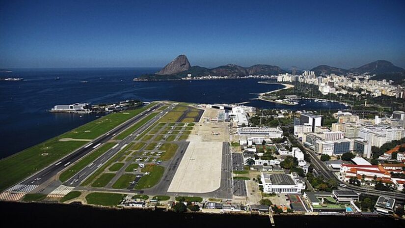 O Aeroporto Santos Dumont, no Rio de Janeiro, é amplamente reconhecido não só pela sua localização icônica, mas também pelos estímulos operacionais que impõe, apesar de disputar espaço com o Aeroporto de Galeão.

Situado entre a Baía de Guanabara e as montanhas que cercam a cidade, o aeroporto é um dos mais movimentados do Brasil, mas sua geografia peculiar o coloca entre os mais desafiadores para pousos e decolagens.

Nas classificações de aeroportos, o Santos Dumont é frequentemente mencionado como um dos mais críticos em termos de operação. Sua pista curta exige precisão absoluta dos pilotos. 

Qualquer erro de cálculo pode resultar em graves consequências, já que, de um lado, há o mar, e do outro, a área urbana densamente habitada do centro do Rio. 