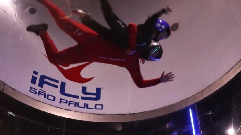 Na iFly São Paulo, o visitante entra em um tubo de ar e tem a sensação real de estar voando. O voo indoor é seguro, acompanhado por instrutores e indicado para todas as idades. Foto: Reprodução/YT/Alpha FM