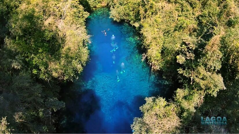 O acesso inclui trilha pela mata, mirante e uma escadaria que leva ao deque sobre a lagoa