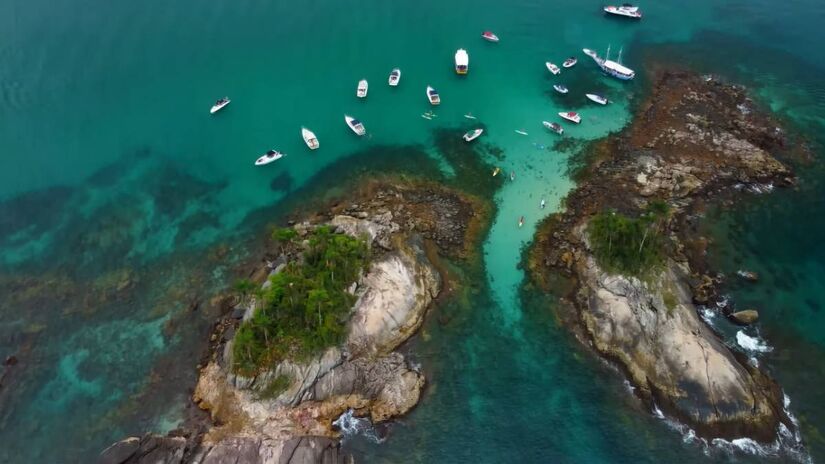 A areia é branca, e a transparência da água, mais distante, faz parecer que o mar é bem mais raso do que realmente é. Porém, não se engane: a região ao redor das ilhas chega a ter 10 metros de profundidade - (Reprodução/YouTube/Aplik Drone)