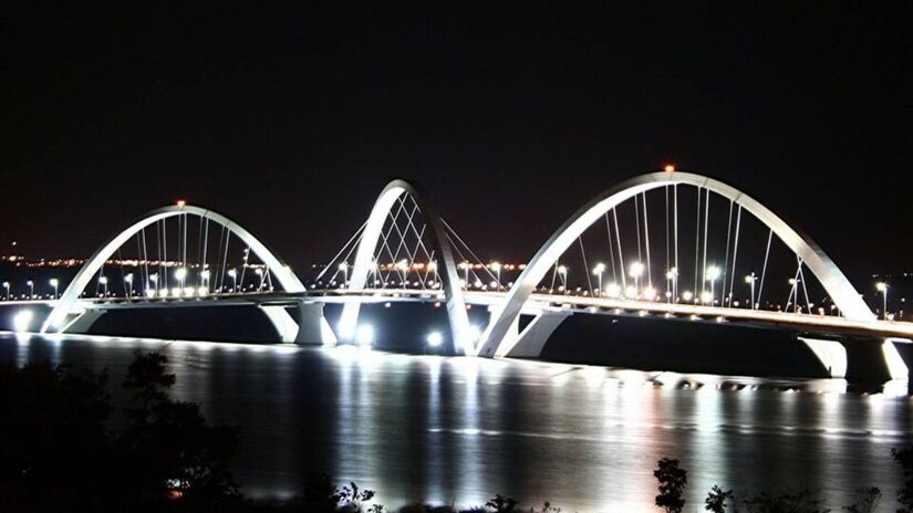 O que para nós é a familiar terceira ponte e rota diária entre o Lago Sul e o centro, para o mundo é agora uma referência oficial de beleza e engenharia. A Ponte JK entrou para o seleto grupo das pontes mais bonitas do planeta segundo a Condé Nast Traveler. Inaugurada em 2002 e custando cerca de 160 milhões de reais, a estrutura se consolidou como um dos cinco pontos mais fotografados do Distrito Federal e segue sendo um cartão-postal obrigatório que enche de orgulho os moradores e encanta quem visita a capital. Fotos: Wikimedia Commons