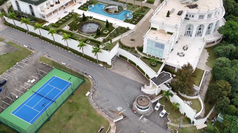 Na parte exterior, o luxo continua, com várias múltiplas piscinas distribuídas pela propriedade. Uma quadra de tênis e uma sala de cinema para até 50 pessoas complementam as opções de entretenimento e lazer dentro do espaço - (Reprodução/YouTube Drone.v7)