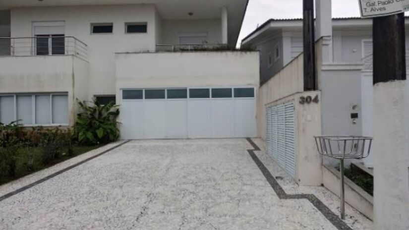 Casa oferece uma fachada revestida em pintura látex sobre massa batida e painéis de vidros temperados.