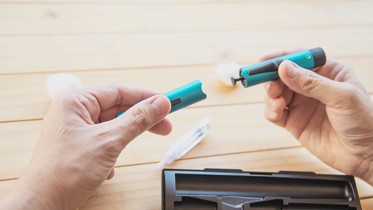 Mãos masculinas seguram caneta para diabete desmontada