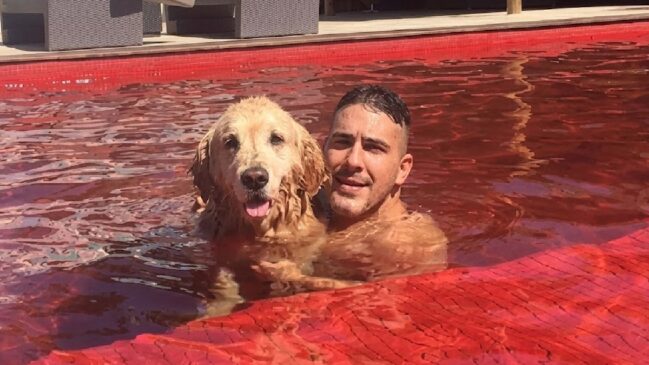 André Marques com o cachorro aproveitando a piscina de cor vermelha