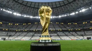 Troféu da Copa do Mundo posada com as arquibancadas de um estádio de fundo