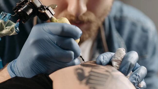 Tatuador fazendo tatuagem em um braço