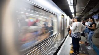 Passageiros aguardam na plataforma do Metrô de São Paulo enquanto um trem passa pela estação