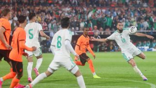 Jogadores da Argélia em amistoso. Ao redor, há atletas da Holanda no campo durante a partida