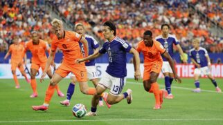 Jogador japones corre com a bola e jogadores holandeses o marcam durante confronto da Copa do Mundo
