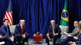 Lula e Trump em reunião em evento internacional, sentados juntos a respectivas equipes