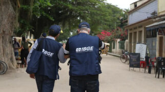 Agentes do IBGE caminham por rua residencial durante atividade de coleta de dados e pesquisas domiciliares