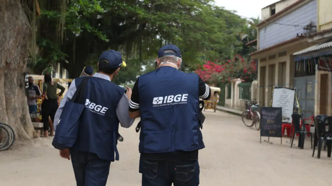 Agentes do IBGE caminham por rua residencial durante atividade de coleta de dados e pesquisas domiciliares