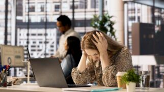 Mulher estressada com as mãos na cabeça em um ambiente corporativo