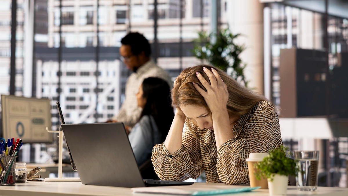 Mulher estressada com as mãos na cabeça em um ambiente corporativo