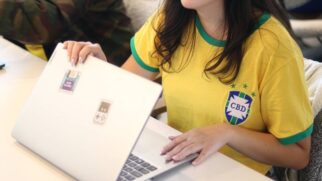 Trabalhadora com a camisa do Brasil fechando o notebook de trabalho