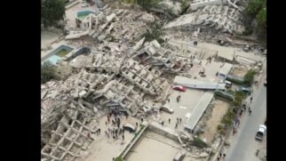 Imagem aérea mostra prédios completamente destruídos após terremoto na Venezuela, com equipes circulando entre os escombros