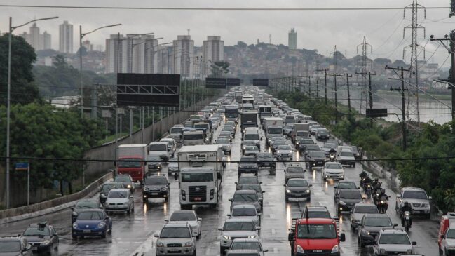 Trânsito intenso em pista molhada durante dia chuvoso em São Paulo, com congestionamento em uma das principais vias da capital