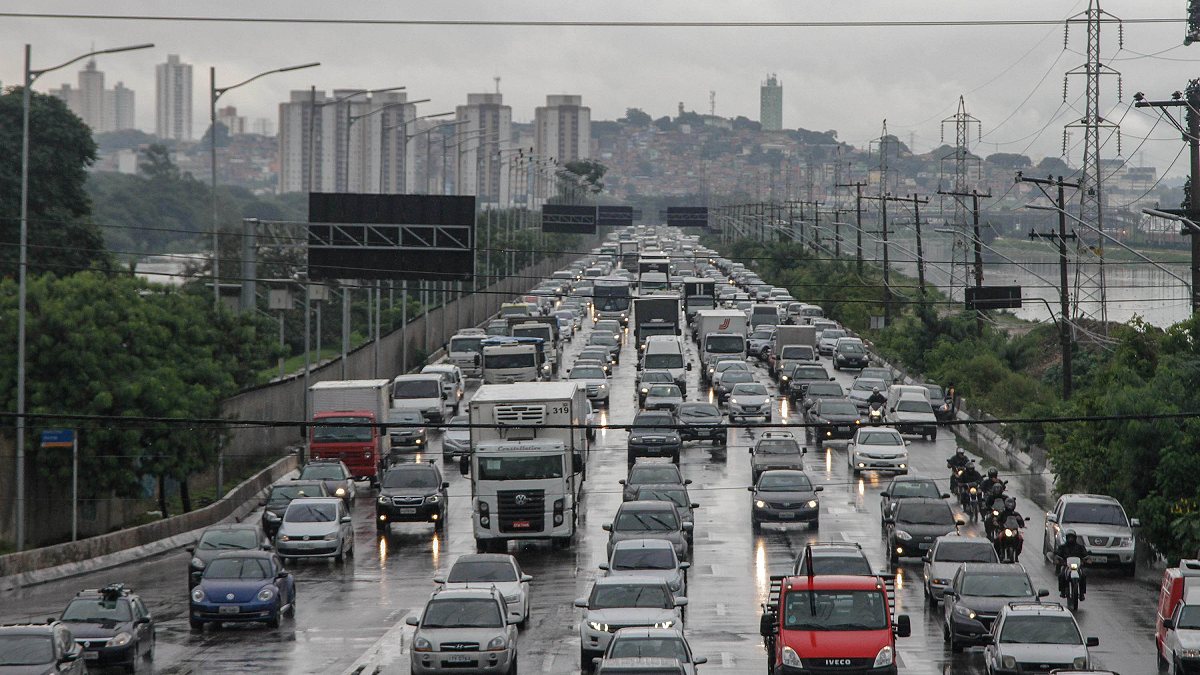 Trânsito intenso em pista molhada durante dia chuvoso em São Paulo, com congestionamento em uma das principais vias da capital