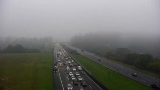 Rodovia registra trânsito intenso sob forte neblina em trecho de serra, com baixa visibilidade e fluxo lento de veículos